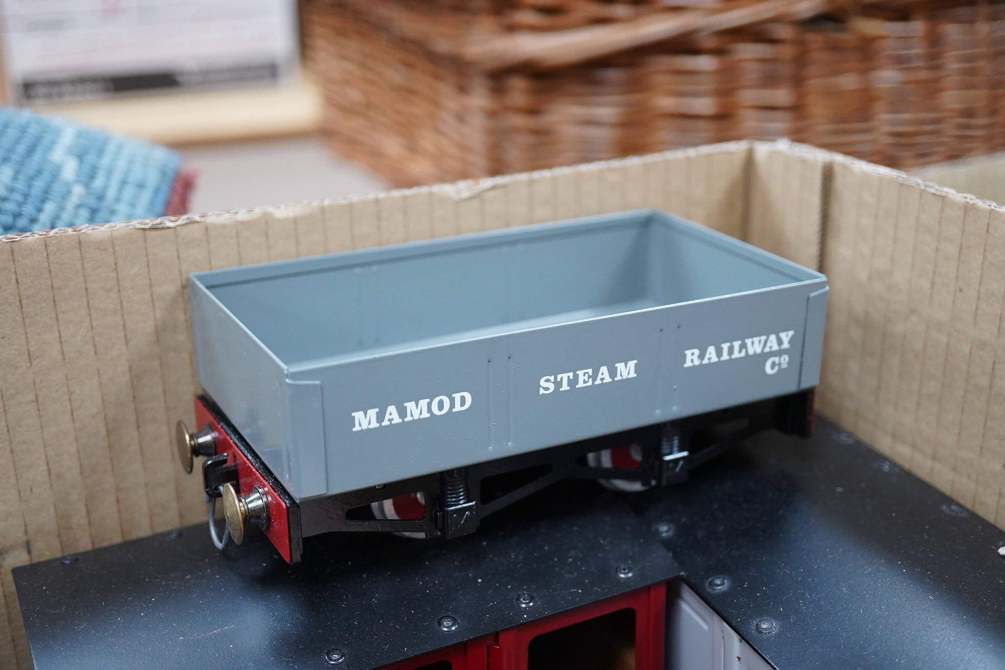 Nine Mamod narrow gauge coaches and freight wagons running on 32mm rails, comprising; three maroon painted 4-wheel coaches, two box vans, a guard’s van, two open wagons and a flatbed with log load